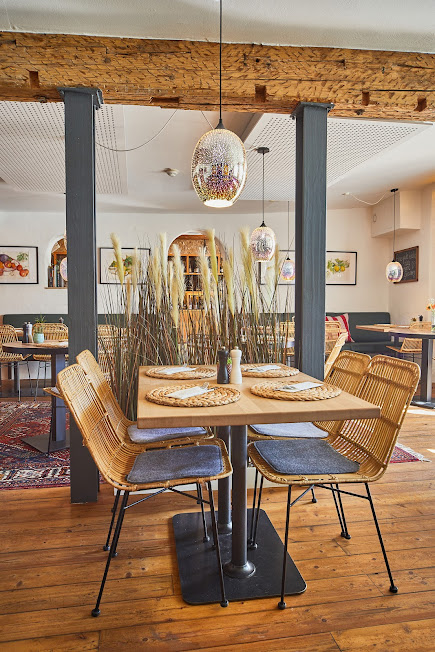 Helles Restaurant mit Rattanstühlen und Holzbalken