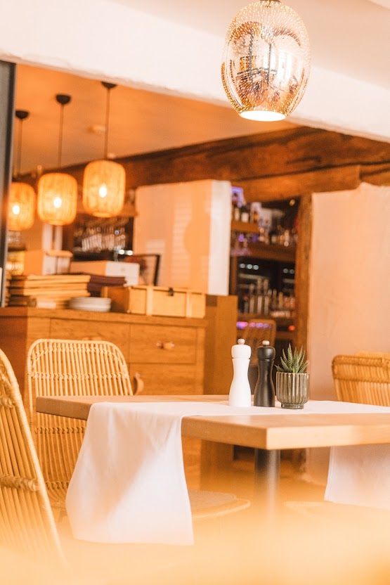 Warmes Restaurantambiente im Weinforum Franken mit Rattanstühlen, Pendelleuchten und stilvoll gedeckten Tischen