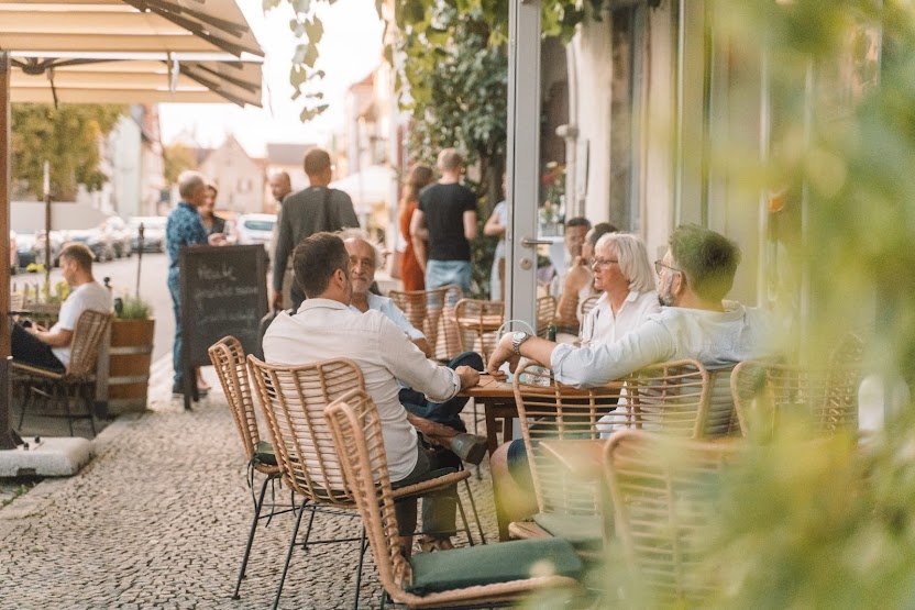 Geselliger Sommerabend auf der Außenterrasse am Marktplatz Eibelstadt – Gäste genießen das Restaurant Weinforum Franken